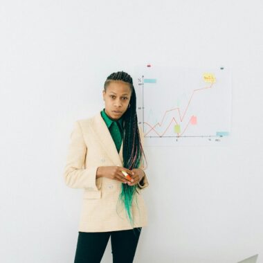 Businesswoman analyzing charts in an office setting with a laptop and diagrams.